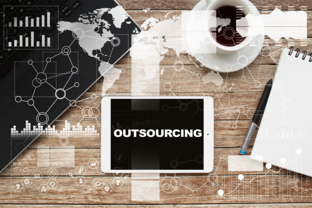 Tablet on desktop with outsourcing text.