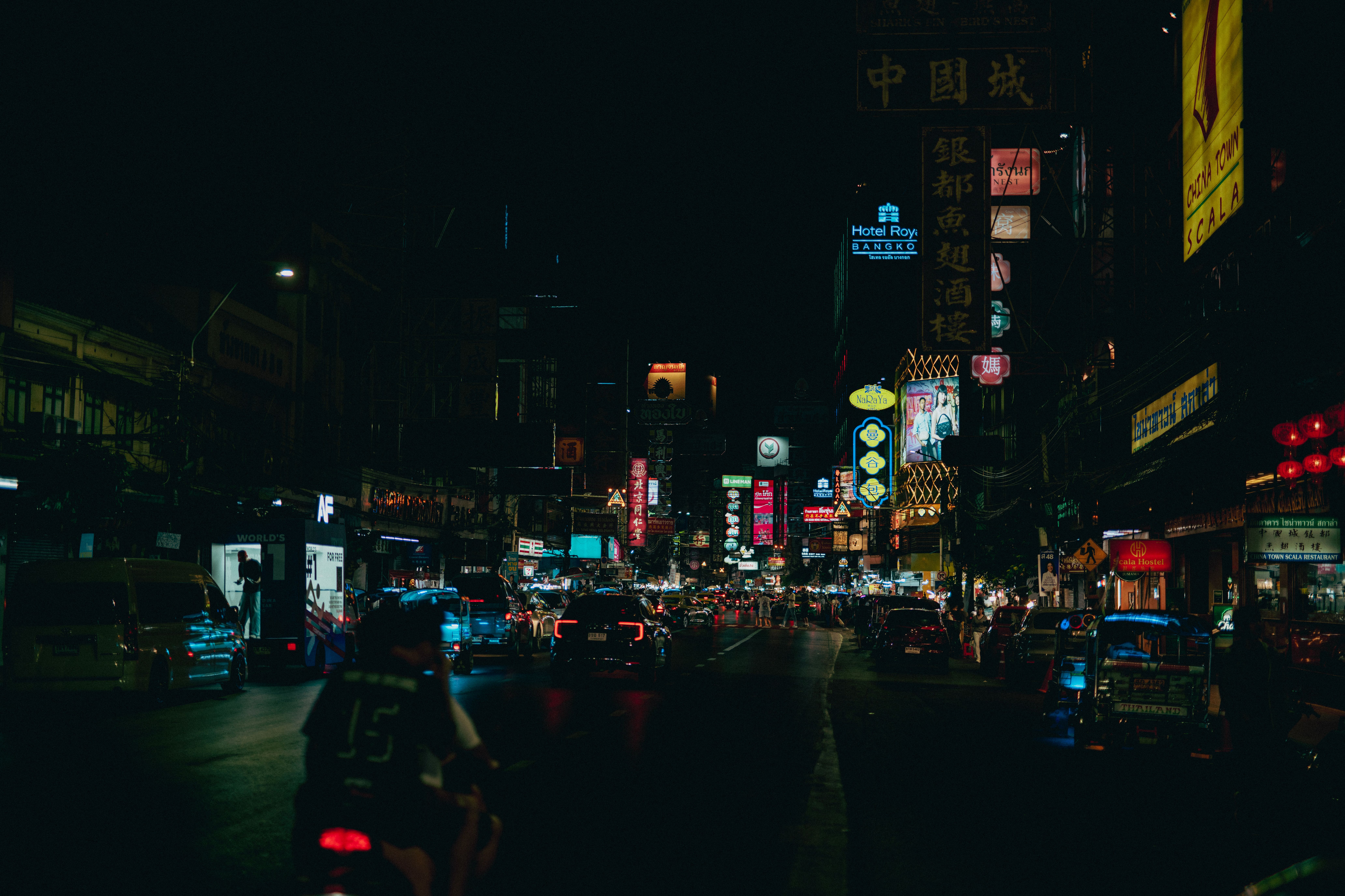 Bangkok Chinatown street glowing with neon signs, traffic, and nighttime energy.