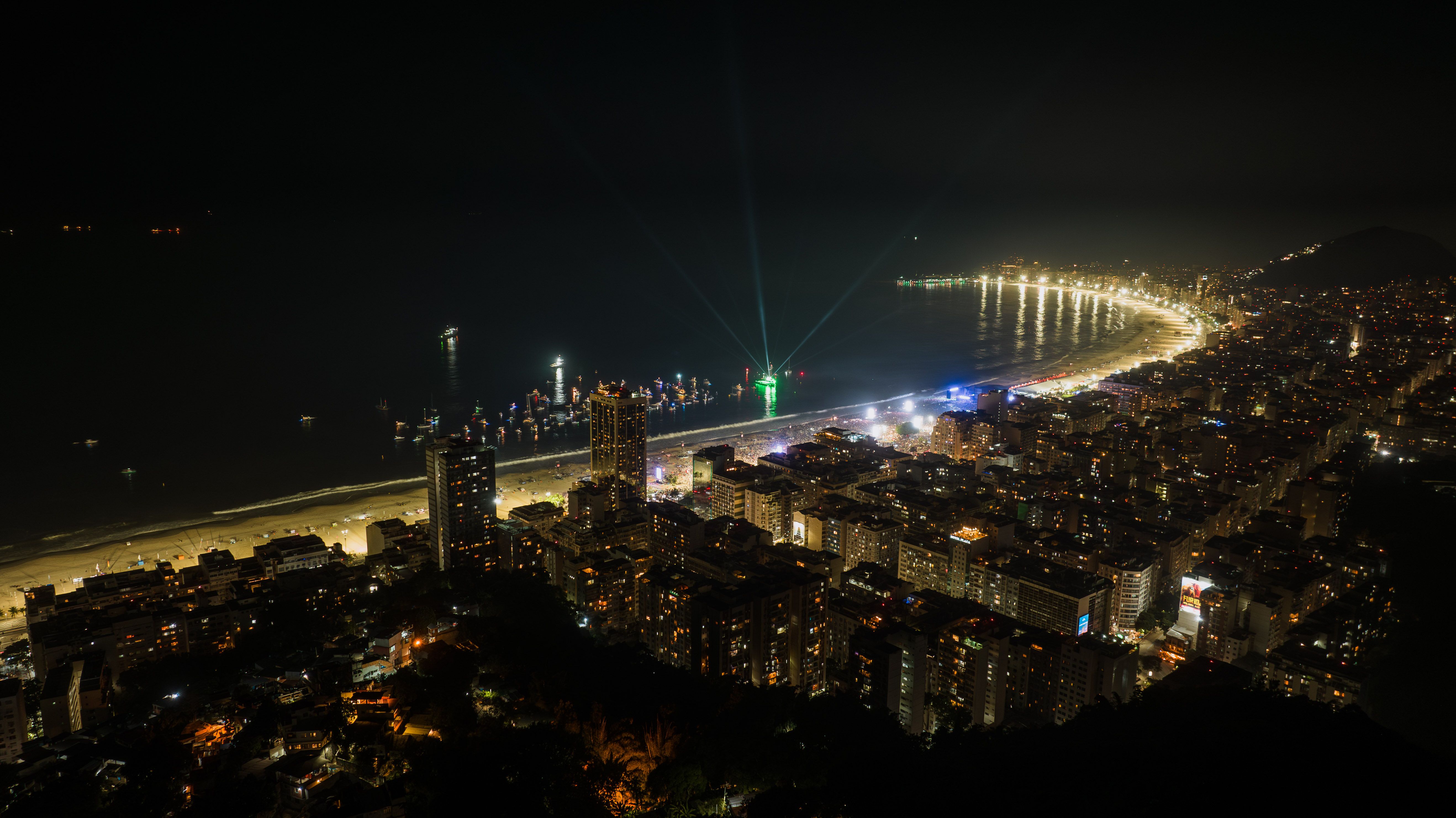 Aerial nighttime view of Rio de Janeiro's illuminated coastline and lively urban waterfront.